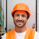 Smiling Fixupae technician in an orange safety helmet and vest